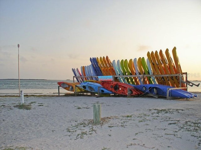 playground at dusk featuring a water view and a view of the beach