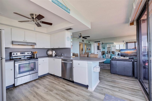 kitchen with stainless steel appliances, a textured ceiling, white cabinets, kitchen peninsula, and light wood-type flooring