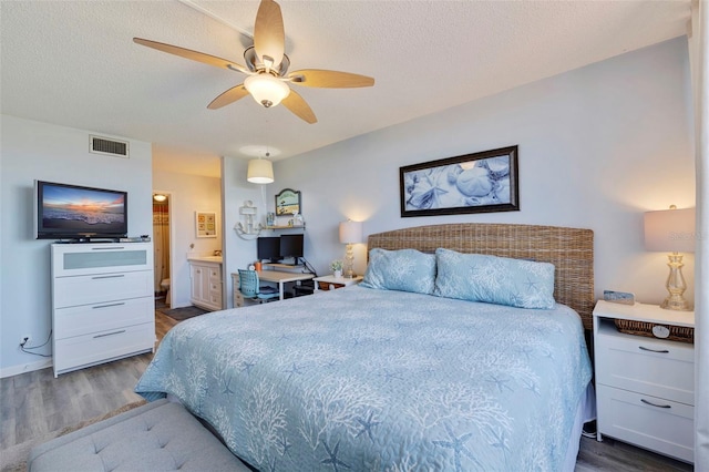 bedroom featuring ceiling fan, ensuite bathroom, dark hardwood / wood-style flooring, and a textured ceiling