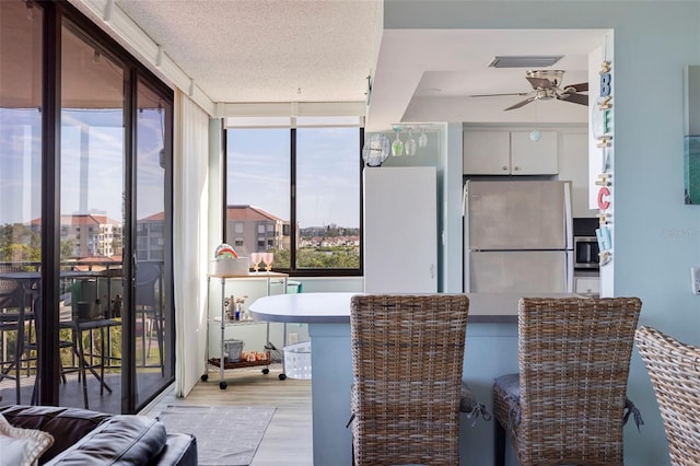 interior space featuring a textured ceiling, white cabinetry, appliances with stainless steel finishes, light wood finished floors, and ceiling fan