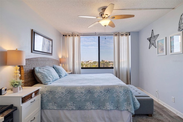 bedroom featuring baseboards, a textured ceiling, dark wood finished floors, and a ceiling fan
