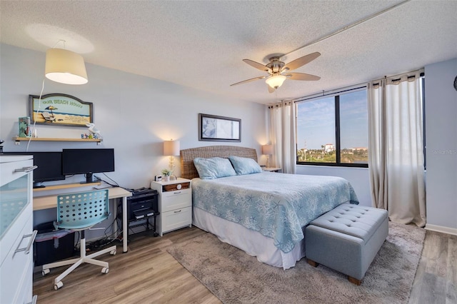 bedroom with a textured ceiling, light wood-type flooring, and ceiling fan