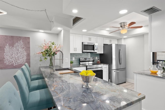 kitchen with ceiling fan, stainless steel appliances, backsplash, sink, and white cabinets