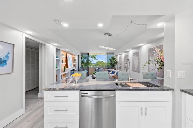 kitchen with dark stone counters, white cabinetry, stainless steel dishwasher, and light hardwood / wood-style floors