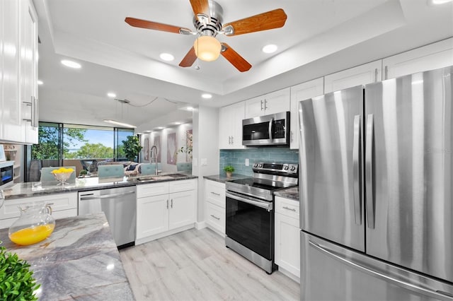 kitchen featuring tasteful backsplash, ceiling fan, stainless steel appliances, light hardwood / wood-style floors, and sink