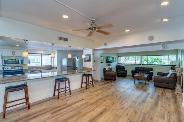 living room featuring ceiling fan, sink, and light hardwood / wood-style flooring