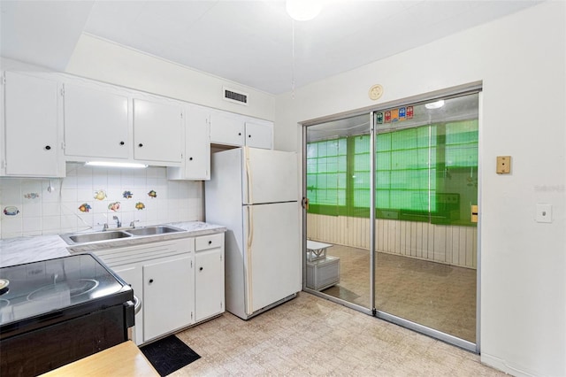 kitchen with backsplash, white fridge, sink, white cabinets, and range with electric stovetop