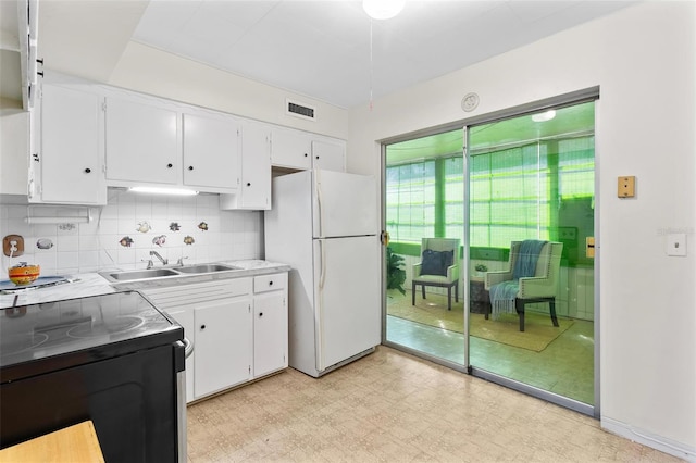 kitchen featuring light floors, white cabinetry, a sink, and freestanding refrigerator