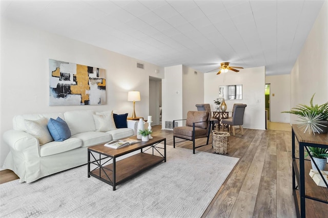 living area with hardwood / wood-style flooring, ceiling fan, and visible vents