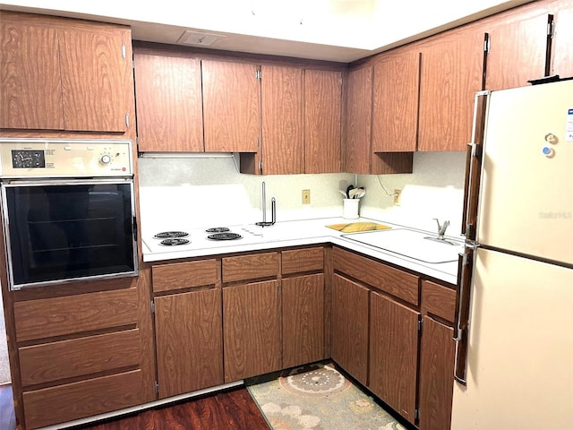 kitchen with sink, white appliances, tasteful backsplash, and dark hardwood / wood-style floors