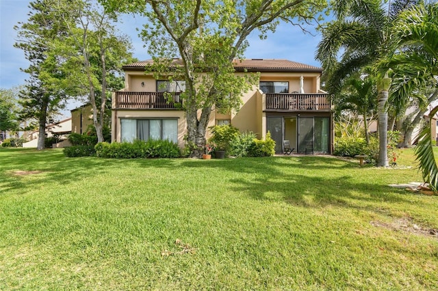 back of house featuring a balcony and a yard