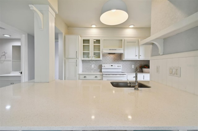 kitchen featuring decorative backsplash, range with electric cooktop, light stone counters, sink, and white cabinetry