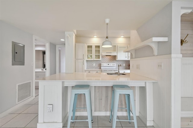 kitchen with a kitchen breakfast bar, sink, range, electric panel, and hanging light fixtures