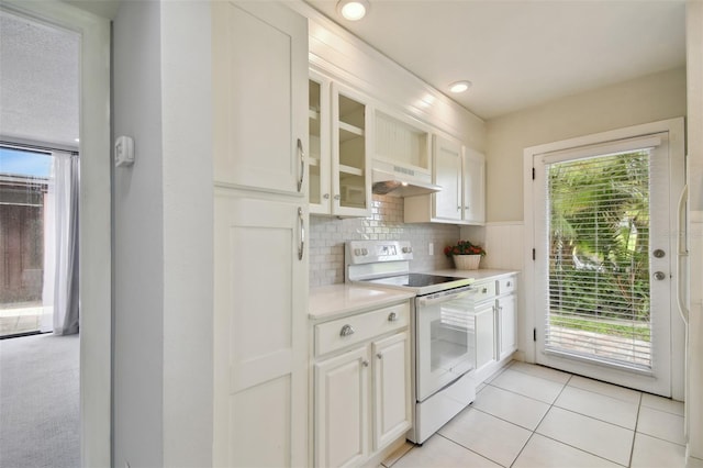 kitchen featuring white electric range oven, white cabinets, and range hood