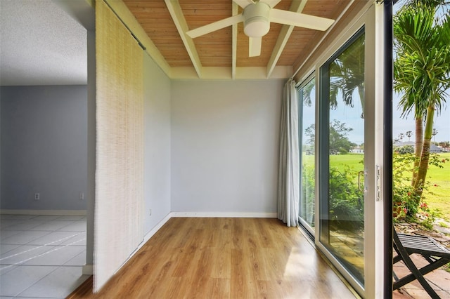 unfurnished sunroom featuring ceiling fan, beamed ceiling, and wood ceiling