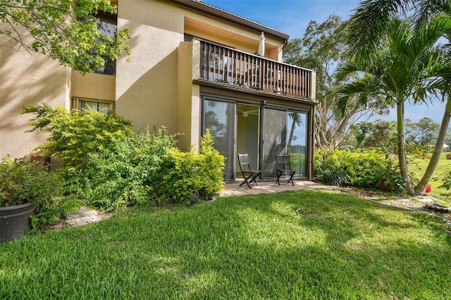 rear view of house with a yard and a balcony