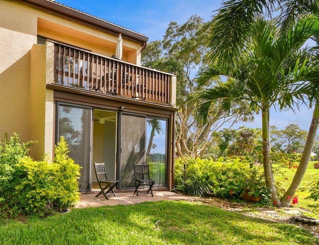 back of property featuring a yard and a balcony