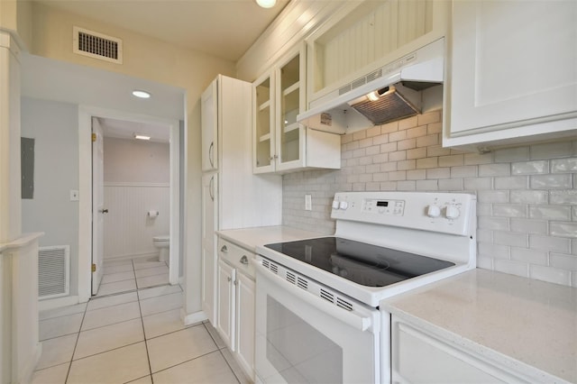 kitchen with white electric range oven, custom range hood, light tile patterned floors, white cabinets, and electric panel