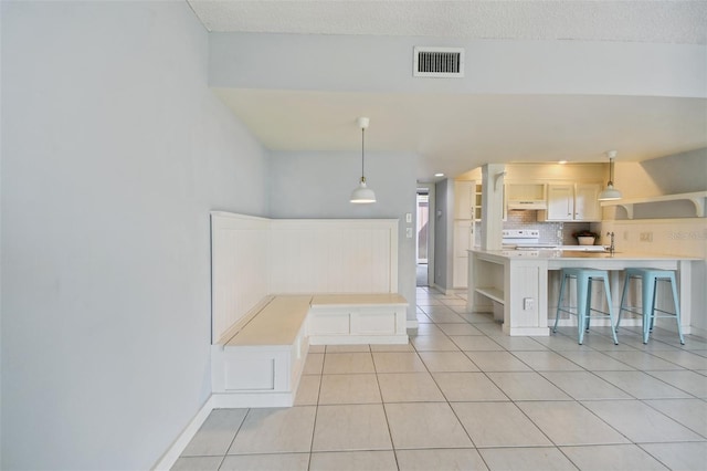 kitchen with sink, hanging light fixtures, decorative backsplash, light tile patterned floors, and range