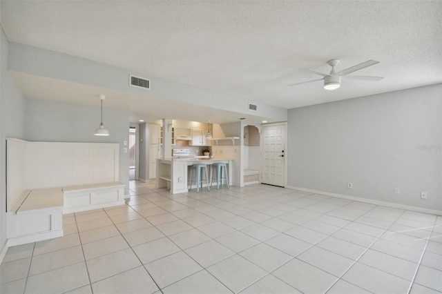 unfurnished living room with ceiling fan, light tile patterned flooring, and a textured ceiling