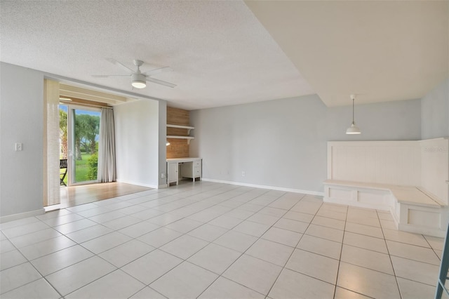 unfurnished living room with ceiling fan, light tile patterned flooring, and a textured ceiling