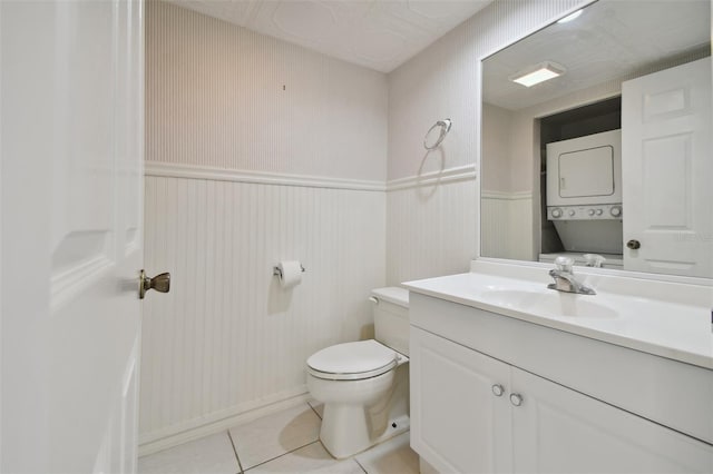 bathroom with tile patterned floors, stacked washer / drying machine, toilet, and vanity