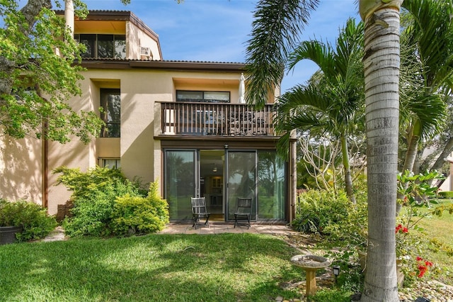 back of property featuring a balcony and a yard