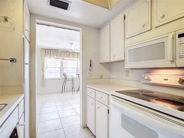 kitchen featuring light tile floors, white cabinets, and white appliances