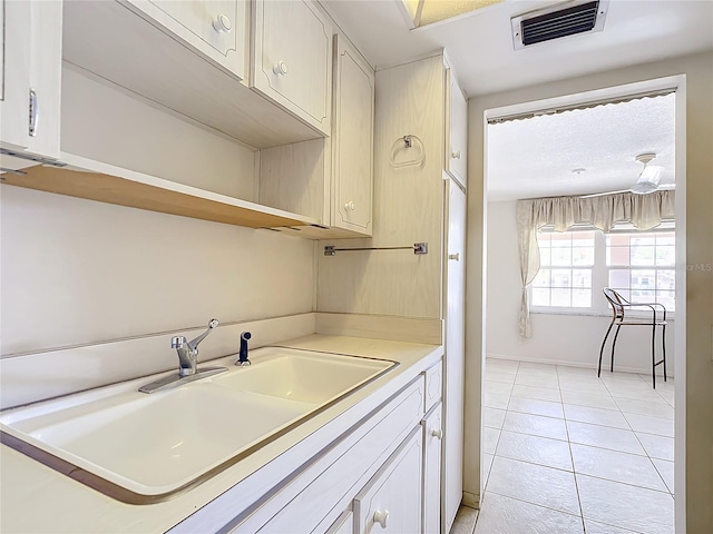 kitchen featuring sink, light tile floors, and white cabinets