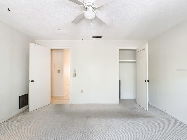 unfurnished bedroom with ceiling fan, a textured ceiling, light colored carpet, and a closet