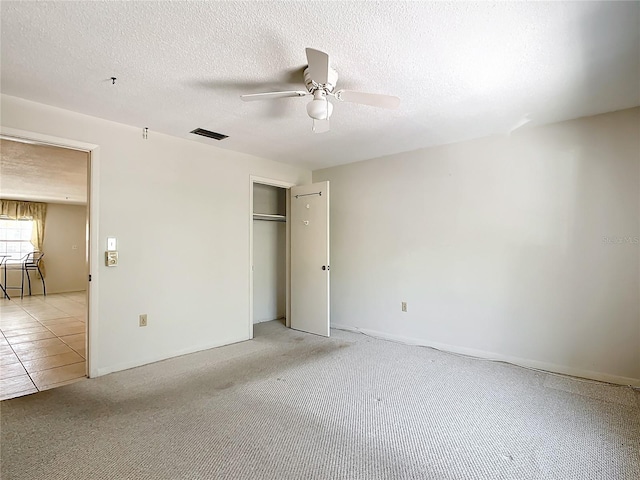 unfurnished bedroom featuring light tile floors, a textured ceiling, a closet, and ceiling fan