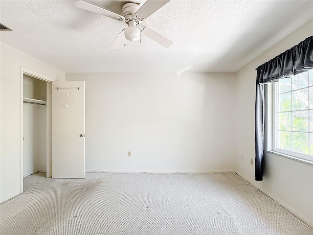 unfurnished bedroom featuring ceiling fan, a closet, light carpet, and a textured ceiling