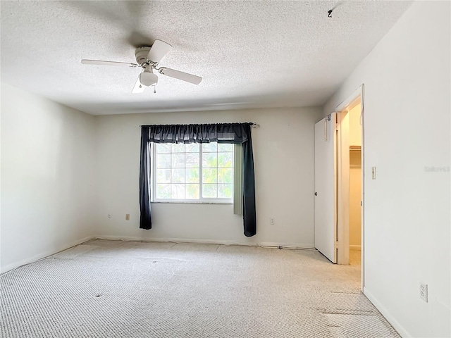 unfurnished room with ceiling fan, light carpet, and a textured ceiling