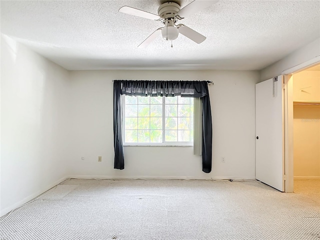 carpeted empty room with ceiling fan and a textured ceiling