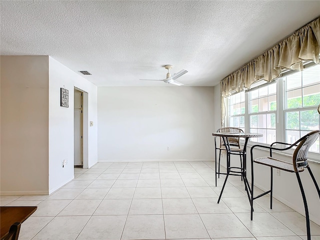 tiled dining room featuring ceiling fan and a textured ceiling