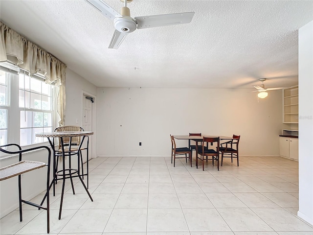 dining room featuring ceiling fan, light tile flooring, and a textured ceiling