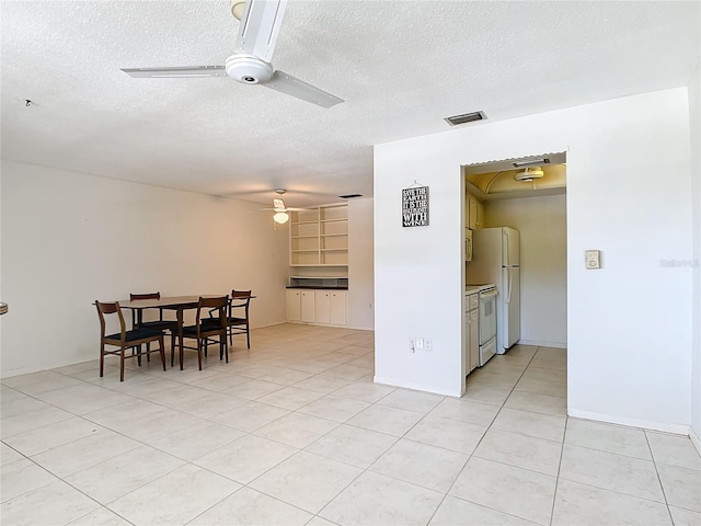 spare room featuring a textured ceiling, ceiling fan, and light tile flooring