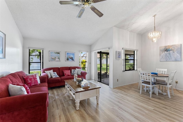 living room featuring light hardwood / wood-style flooring, a textured ceiling, lofted ceiling, and ceiling fan with notable chandelier