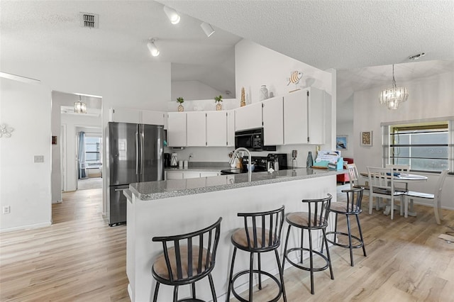 kitchen featuring light hardwood / wood-style floors, a textured ceiling, stainless steel fridge, hanging light fixtures, and an inviting chandelier