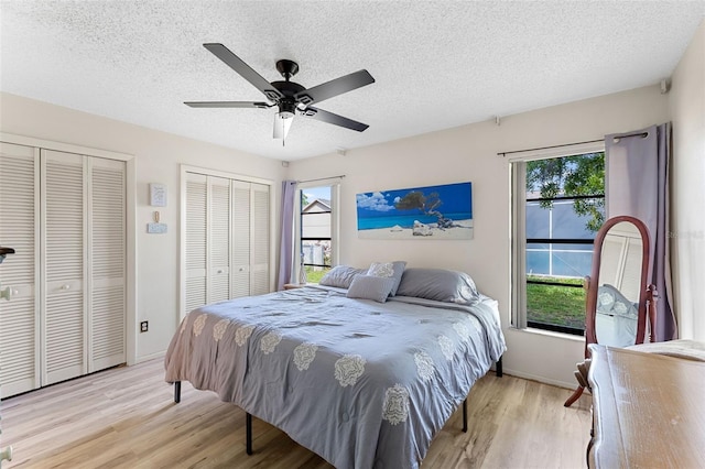 bedroom featuring multiple windows, multiple closets, and light hardwood / wood-style flooring