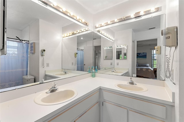 bathroom with oversized vanity, toilet, and dual sinks