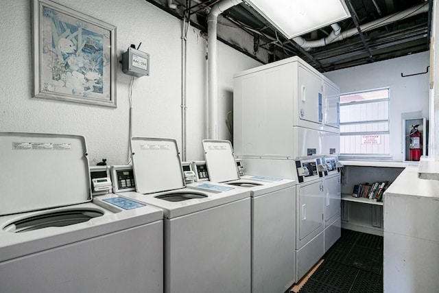 washroom featuring dark tile floors, stacked washing maching and dryer, and washing machine and clothes dryer