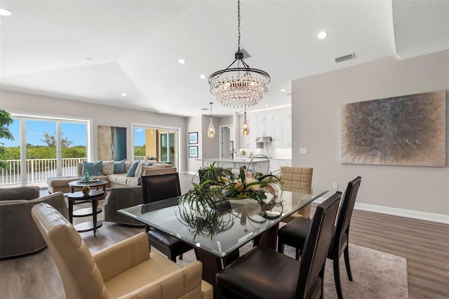 dining area with hardwood / wood-style floors, lofted ceiling, a textured ceiling, a chandelier, and sink