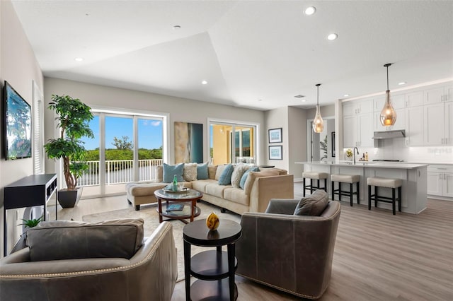 living room with vaulted ceiling, sink, and hardwood / wood-style flooring