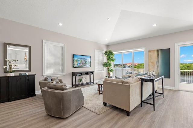 living room with vaulted ceiling, a healthy amount of sunlight, and light hardwood / wood-style flooring