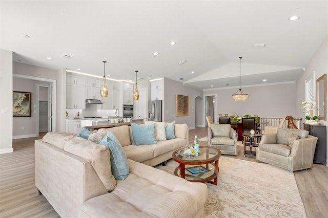 living room with sink, light hardwood / wood-style flooring, and lofted ceiling