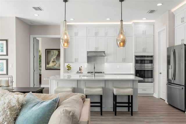 kitchen featuring stainless steel appliances, pendant lighting, and white cabinets