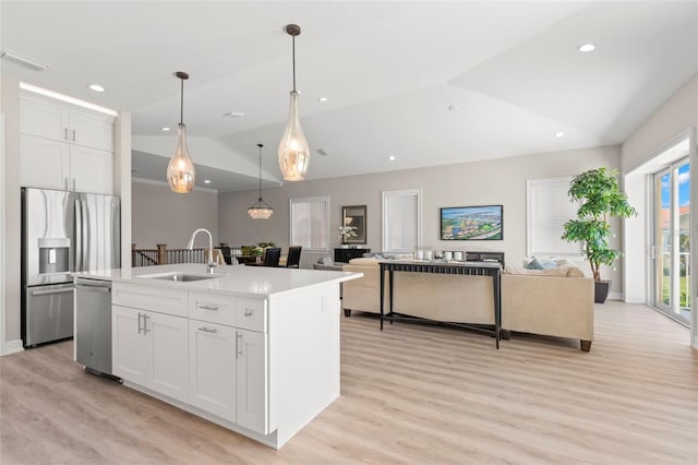 kitchen with vaulted ceiling, sink, a kitchen island with sink, stainless steel appliances, and white cabinets