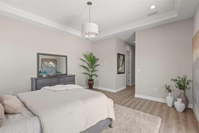 bedroom with light hardwood / wood-style floors, a tray ceiling, and ornamental molding