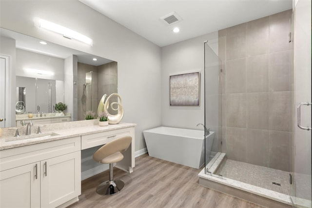 bathroom with hardwood / wood-style floors, separate shower and tub, and vanity